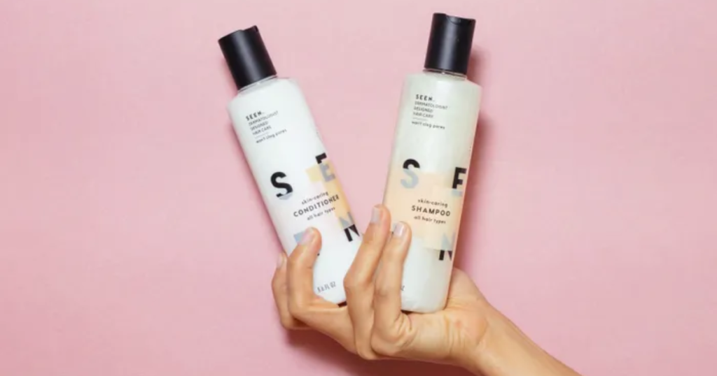 a hand holding bottles of seen shampoo and conditioner
