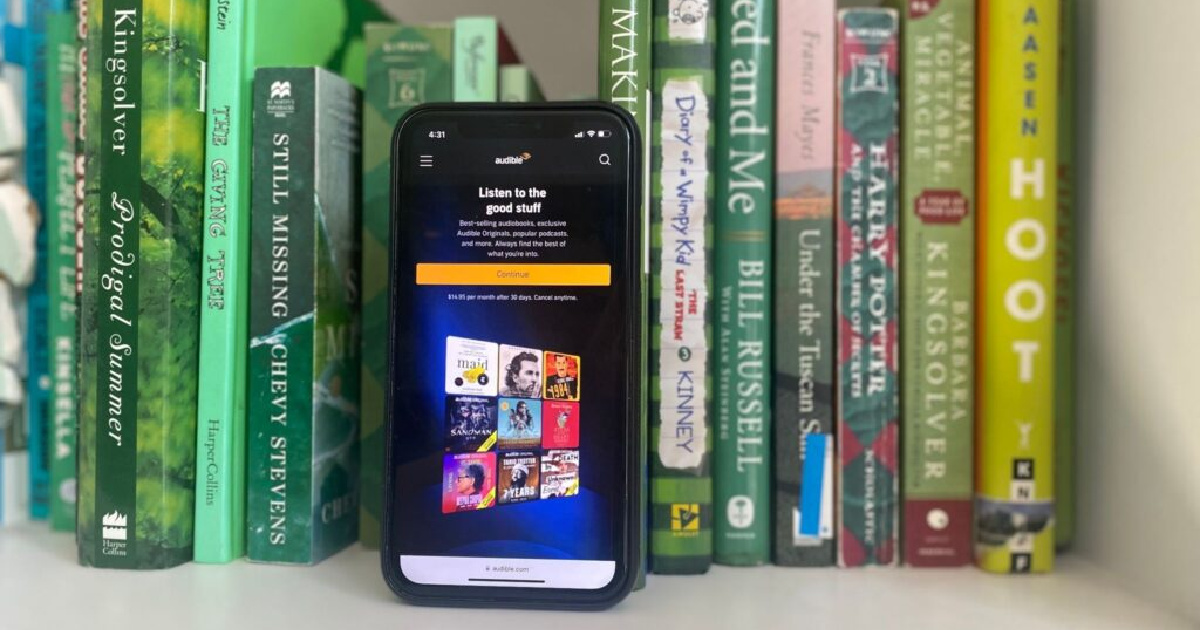 phone with Audible app leaning against a row of books