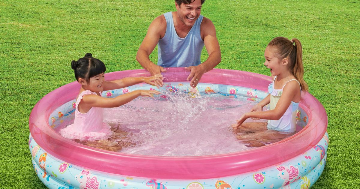 two kids and an adult playing in a pool