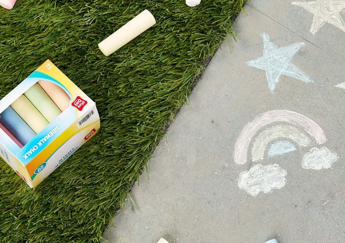 box of chalk on the grass with pieces of chalk around it