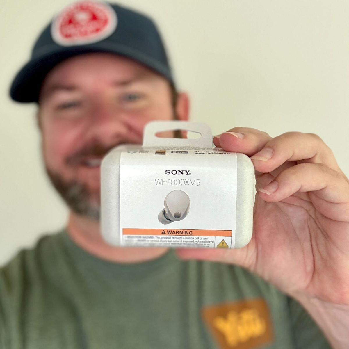 man holding a pair of Sony earbuds