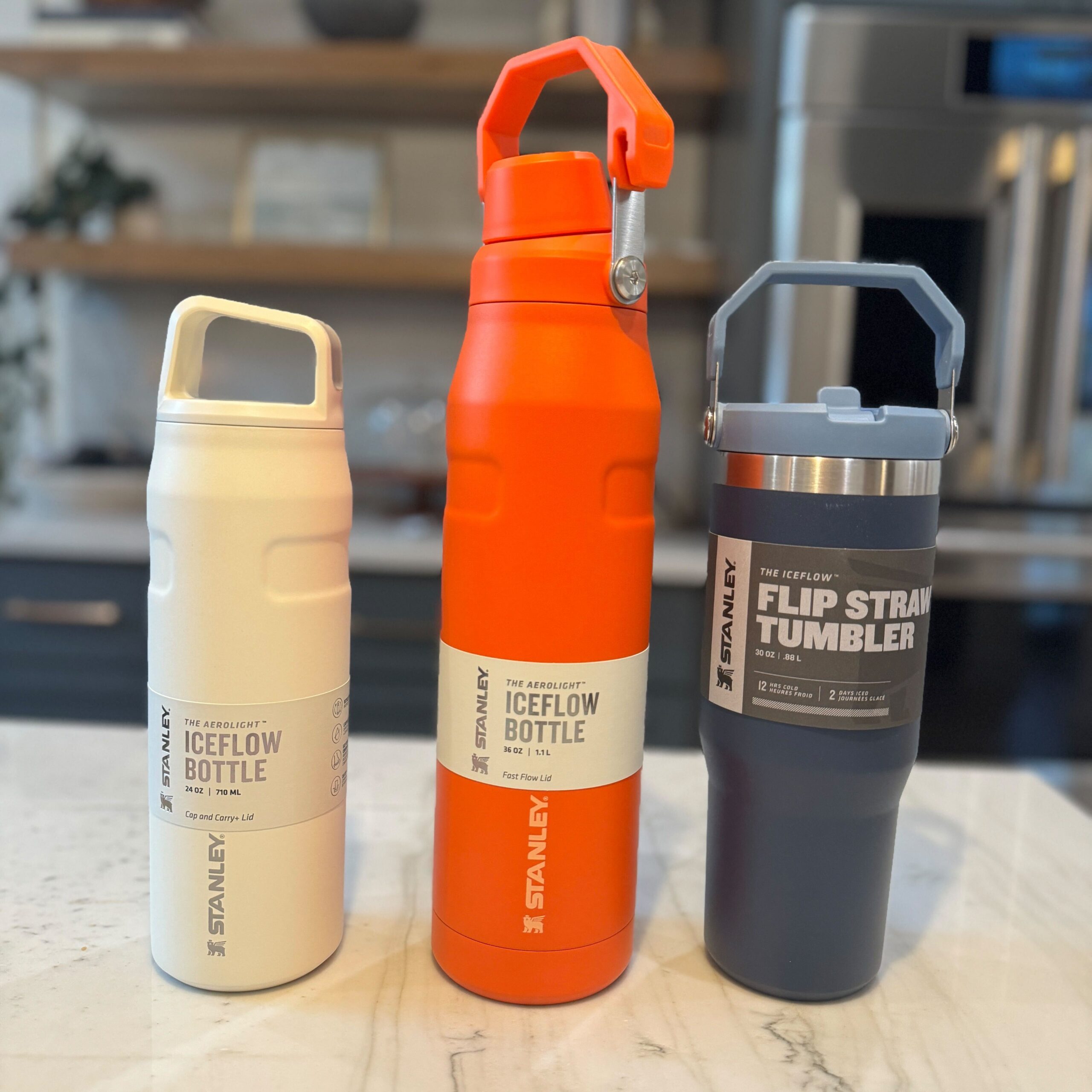 Three different Stanley brand water bottles sitting on a counter