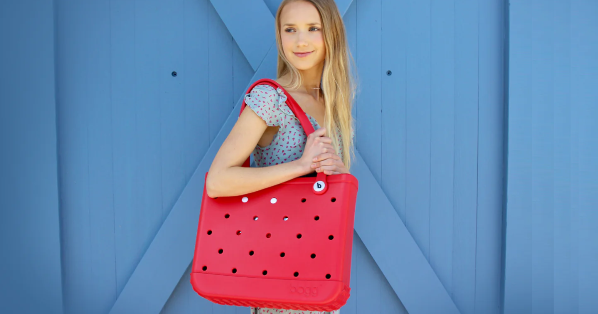woman standing holding bogg bag in red