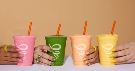 hands on a table each holding a different flavor of jamba juice smoothie