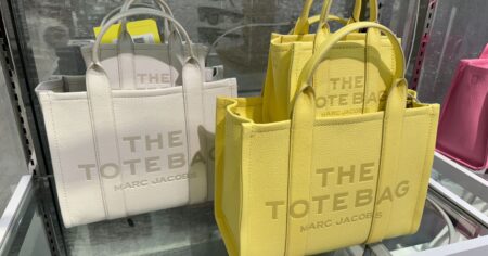 white and yellow marc jacobs the tote bags sitting on a shelf