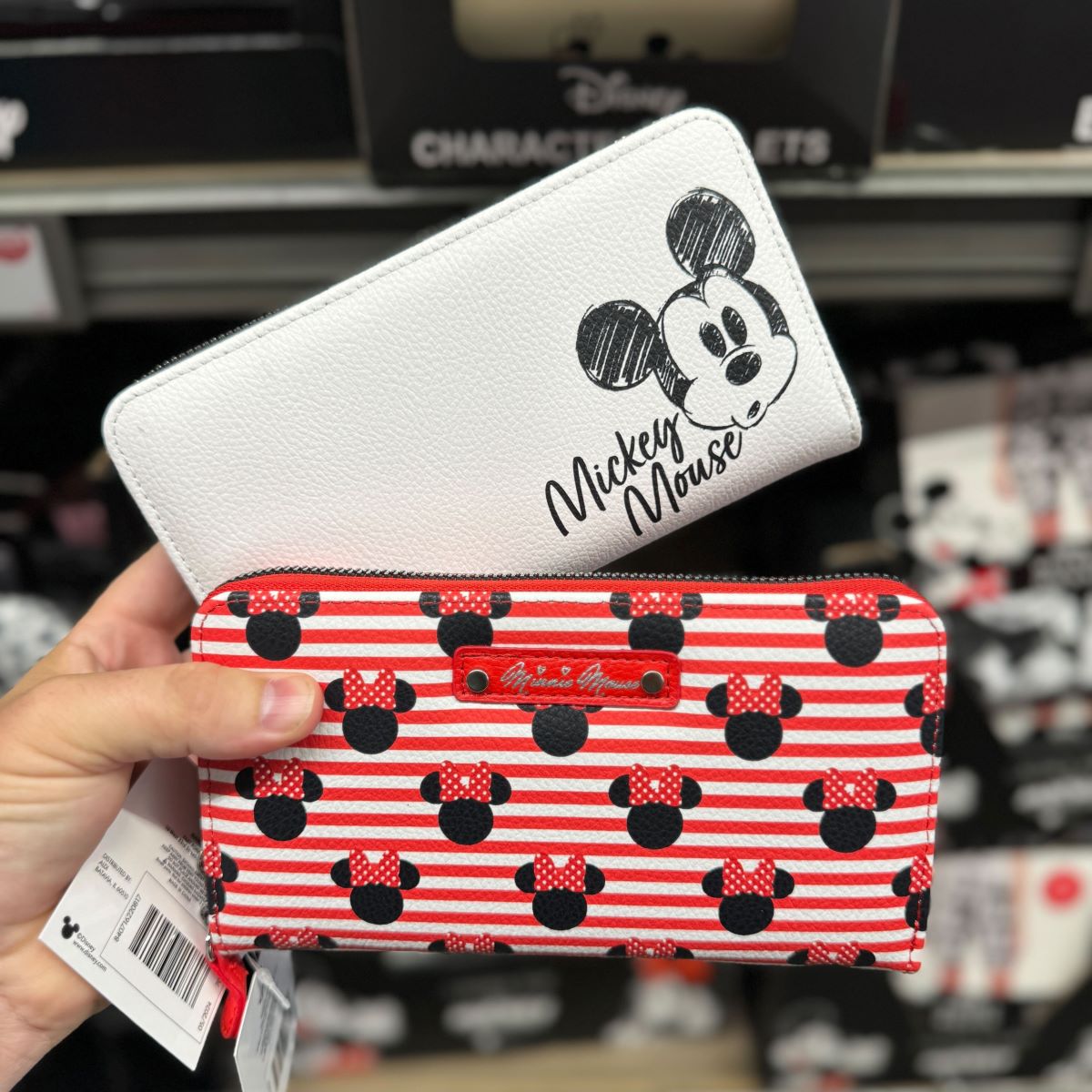 hand holding two Disney wallets