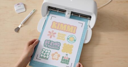 hand holding a Cricut mat with sticker paper on it