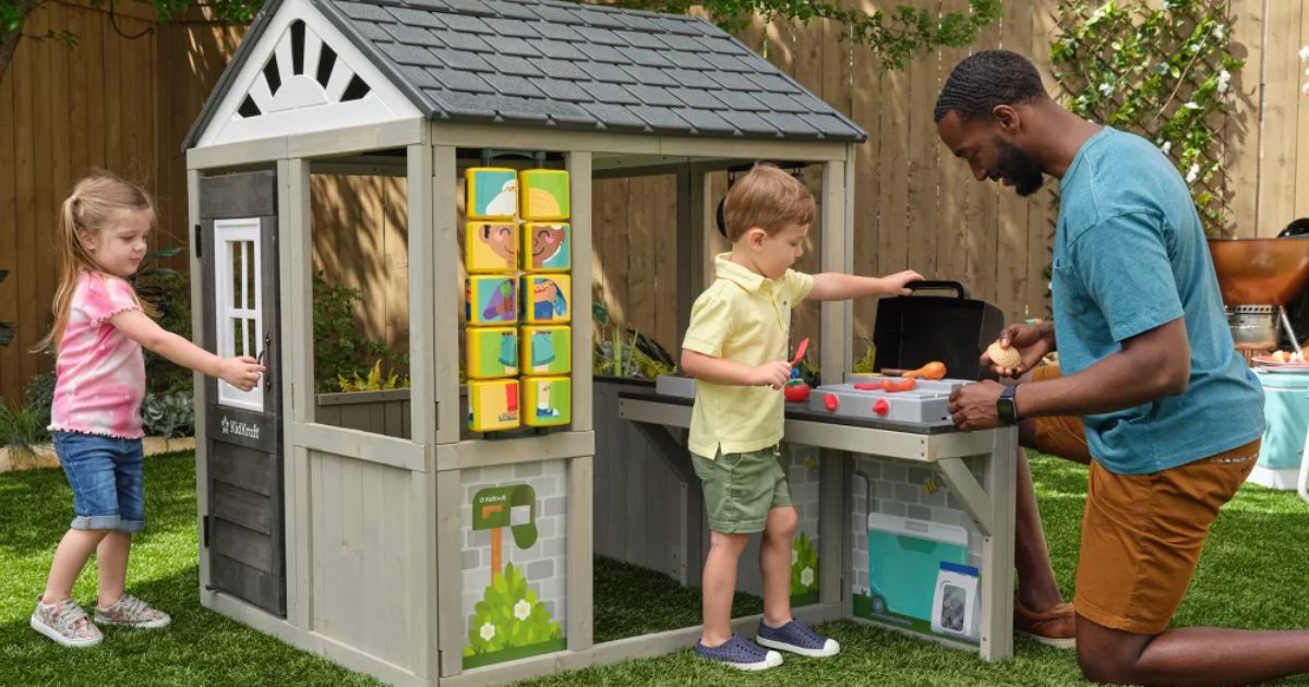 two kids and an adult playing in an outdoor playhouse