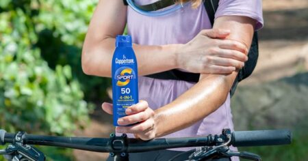 person on a bike holding a Coppertone sunscreen spray