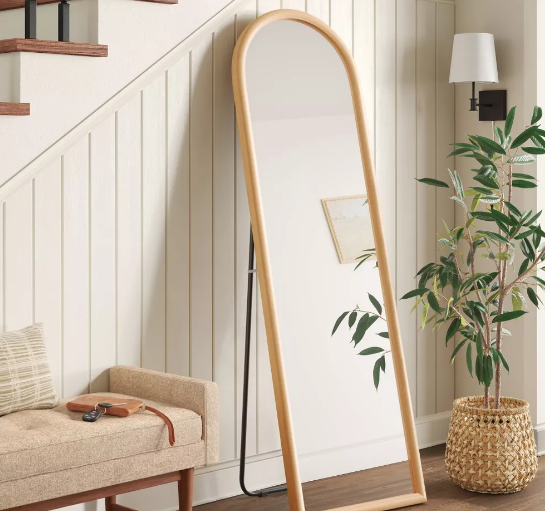 mirror leaning on a wall by an ottoman