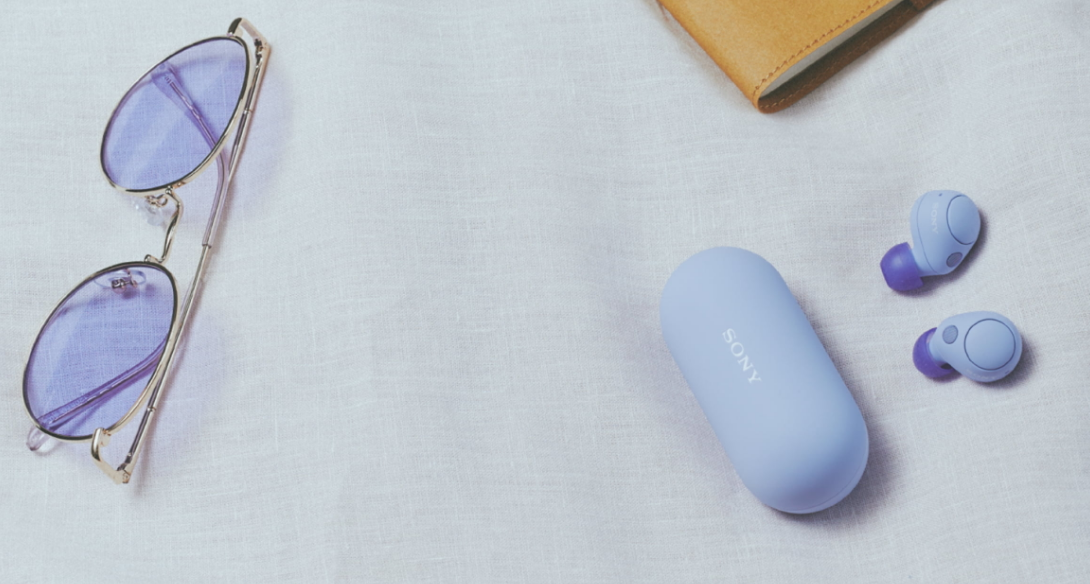 earbuds next to a case and a pair of sunglasses