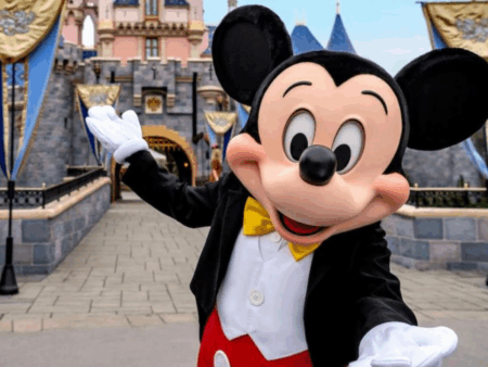 Mickey Mouse standing in front of Disneyland castle
