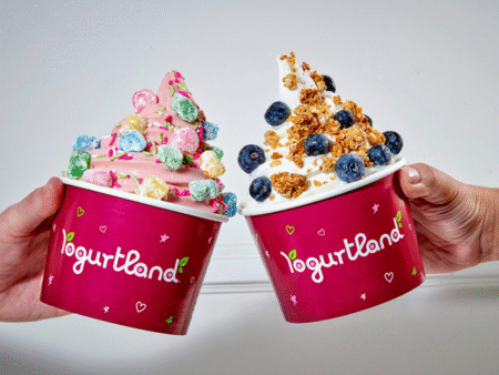 2 People holding Yogurtland Yogurt Cups